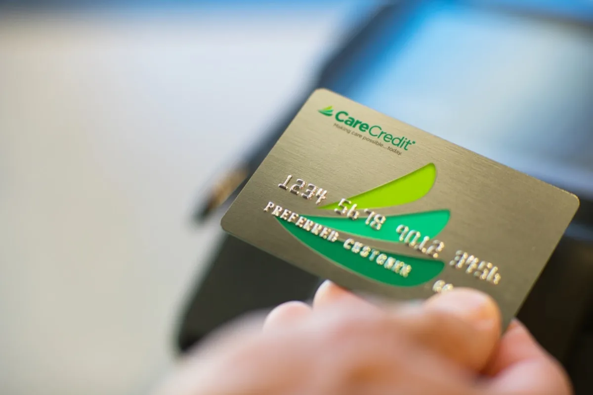 A gold CareCredit card being used at a payment terminal